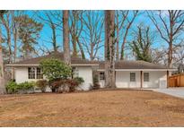 Charming single-story home featuring a white painted brick exterior and a well-maintained front yard with mature trees at 1119 Oakdale Se Dr, Smyrna, GA 30080