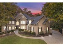 Elegant home exterior featuring stone accents, well-manicured landscaping and circular driveway at 580 Meadows Creek Dr, Johns Creek, GA 30005