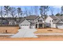 Two-story house with gray siding, three-car garage, and landscaping at 11 Ramble Way, Sharpsburg, GA 30277