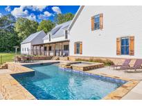 Stunning backyard pool and hot tub with outdoor seating and manicured landscaping, perfect for entertaining at 2731 Tribble Mill Rd, Lawrenceville, GA 30045