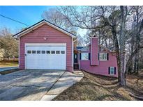 Pink house with attached garage and landscaped yard at 1005 Quail Dr, Stockbridge, GA 30281