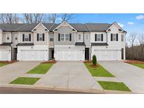 View of townhomes with modern exteriors, well-manicured lawns, driveways, and attached garages at 353 Sound Cir, Stockbridge, GA 30281
