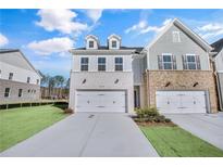 Two-story townhome with brick and siding exterior, two-car garage, and landscaped lawn at 5615 Tillman Way, Powder Springs, GA 30127