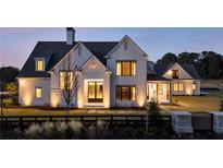 Elegant, modern farmhouse-style home with white painted brick, black trim and lush landscaping at 200 Heatherton Way, Milton, GA 30009