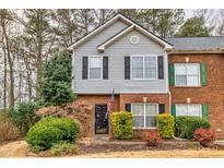 Charming two-story townhome with gray siding, red brick, a black door and manicured landscaping at 4405 Maple Valley Dr, Cumming, GA 30040