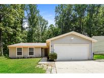 Ranch style home with attached garage and landscaped lawn at 5377 Martins Crossing Rd, Stone Mountain, GA 30088