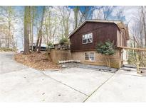 Two-story home with a mix of brick and dark wood, surrounded by trees and a concrete driveway at 3713 Ashford Dunwoody Ne Rd, Brookhaven, GA 30319