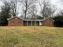 Charming brick home featuring a covered porch, green shutters, and a well-maintained front yard at 517 Toombs St, Palmetto, GA 30268