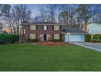 Charming two-story brick home featuring a well-manicured lawn and a two car garage at 5323 Lakesprings Dr, Dunwoody, GA 30338