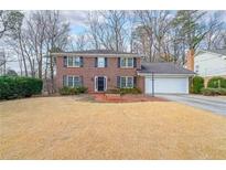 Classic brick home featuring a well-manicured lawn and traditional architectural details at 5323 Lakesprings Dr, Dunwoody, GA 30338