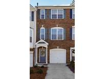 Charming brick townhome featuring a one car garage and a covered front porch with a decorative wreath at 3182 Mill Springs Cir, Buford, GA 30519