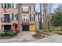 Charming brick townhome featuring black shutters, a yellow front door, and a well-manicured front yard at 3245 Buckhead Forest Ne Mews, Atlanta, GA 30305