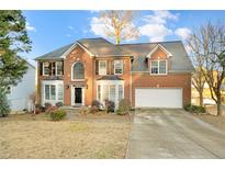 Brick two-story house with a large driveway and landscaped lawn at 2265 Wildwood Lake Dr, Suwanee, GA 30024