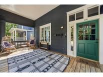 Inviting front porch featuring an outdoor rug, wicker chairs, and stylish gray siding and a green front door at 66 Howell Ne St, Atlanta, GA 30312