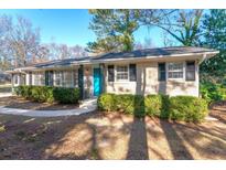Charming brick home featuring manicured hedges and a bright blue front door at 3448 Montreal Way, Tucker, GA 30084