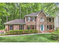 Charming brick two-story home with manicured lawn, verdant landscaping, and a serene wooded backdrop at 4259 Arbor Club Dr, Marietta, GA 30066