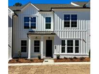 New construction townhome with white vertical siding, black trim, and manicured landscaping at 405 Nettle Ct, Woodstock, GA 30188