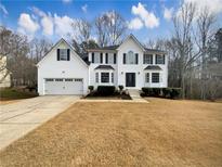 Two-story white house with a three-car garage and landscaped lawn at 7045 Treeline Dr, Cumming, GA 30028