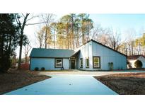 Modern home featuring a long driveway and sleek lines, nestled among mature trees at 2950 Manitoba Ln, Marietta, GA 30062