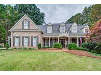 Beautiful brick home featuring a well-manicured lawn and a charming, covered front porch at 9070 Huntcliff Trce, Sandy Springs, GA 30350