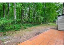 A spacious backyard with a tile patio surrounded by lush trees and greenery offers privacy and outdoor living at 1428 Muirfield Dr, Stone Mountain, GA 30088