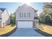 Two-story house with light beige vinyl siding, stone accents, and a two-car garage at 239 Dove Pl, Social Circle, GA 30025