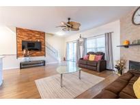 Bright living room featuring hardwood floors, a modern ceiling fan, and a statement wood accent wall with a flatscreen TV at 1605 Signal Flag Way, Lawrenceville, GA 30043