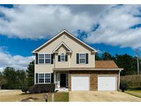 Two-story house with three-car garage, stone accents, and landscaping at 7533 Congregation St, Fairburn, GA 30213