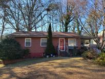 Brick ranch house with a red door, situated on a grassy lot with mature trees at 2369 Springdale Sw Rd, Atlanta, GA 30315