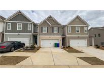 View of townhomes with driveways and garages, showcasing the building's exterior at 7540 Knoll Hollow Rd, Lithonia, GA 30058