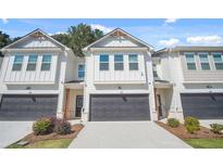 Two-story townhome with white siding, dark gray garage doors, and landscaping at 5536 Rockfern Dr, Lilburn, GA 30047