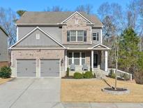 Two-story brick home with gray siding, two-car garage, and landscaped yard at 1868 Lakeview Bend Way, Buford, GA 30519