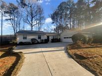 House exterior boasts a white exterior, a driveway, and mature trees at 4095 Maxanne Nw Dr, Kennesaw, GA 30144
