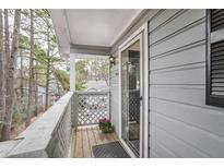 View of the balcony featuring gray wood siding, white railings, and sliding glass door at 204 Natchez Trce, Sandy Springs, GA 30350