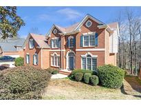 Elegant brick home featuring blue shutters, detailed trim, and a neatly landscaped front yard under a bright, sunny sky at 775 River Cliff Ct, Suwanee, GA 30024