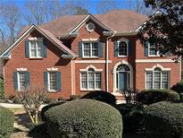 Charming brick home featuring an arched entry, complemented by lush landscaping at 775 River Cliff Ct, Suwanee, GA 30024