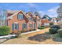 Charming red brick home with blue shutters and a well-maintained front yard at 775 River Cliff Ct, Suwanee, GA 30024