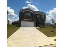 Two-story brick home with a large driveway and landscaped lawn at 266 Broder Farms Dr, Stockbridge, GA 30281