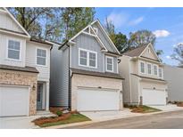 Three-story townhouses with gray and beige siding, two-car garages, and landscaping at 702 Smokey Quartz Way, Kennesaw, GA 30144