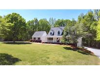 Charming two-story white home boasts a well-manicured lawn, complemented by mature trees and a welcoming front porch at 866 Lee Byrd Rd, Loganville, GA 30052