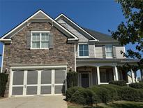 Two-story home with stone and siding accents, three-car garage, and landscaped yard at 4335 Silent Path, Cumming, GA 30028