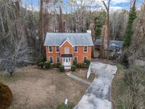 Brick two-story house with driveway and yard, surrounded by trees at 1600 Dillwood Ct, Lithonia, GA 30058