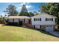 Ranch home with brick and white siding, attached garage, and a well-manicured lawn at 1022 Washington Ave, Woodstock, GA 30188