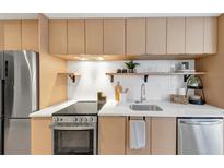 This bright kitchen features stainless steel appliances, modern countertops, and tile backsplash at 1805 Harvard Ave # 306, College Park, GA 30337