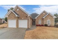 Charming brick home featuring a two-car garage and well-manicured lawn at 217 Chad Ln, Loganville, GA 30052