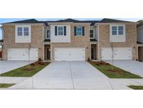 Charming townhome featuring a brick facade, white garage doors, and professional landscaping at 305 Heavenly Hollow Pl, Mcdonough, GA 30253