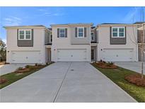 New townhomes with painted brick and gray accents, featuring individual garages and manicured front lawns at 305 Heavenly Hollow Pl, Mcdonough, GA 30253