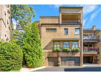 Brick townhouse showcasing private garages, balcony, and lush landscaping at 3631 Habersham Nw Rd, Atlanta, GA 30305