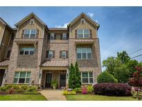 Charming two-story brick townhome featuring beautiful landscaping and a covered front porch at 1365 Hawthorne Se Ave, Smyrna, GA 30080
