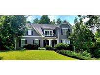 Charming two-story home with gray siding and a well-manicured lawn surrounded by lush greenery at 1037 Creek Side Dr, Canton, GA 30115